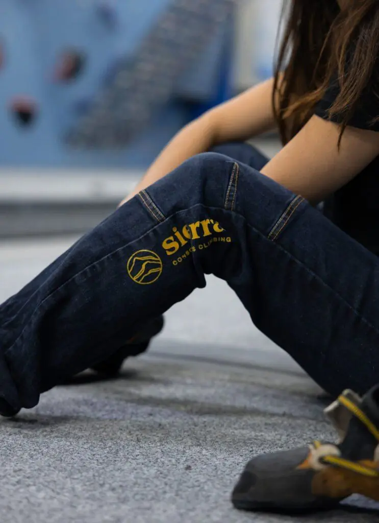 Escaladora sentada en la colchoneta de boulder con pies de gato